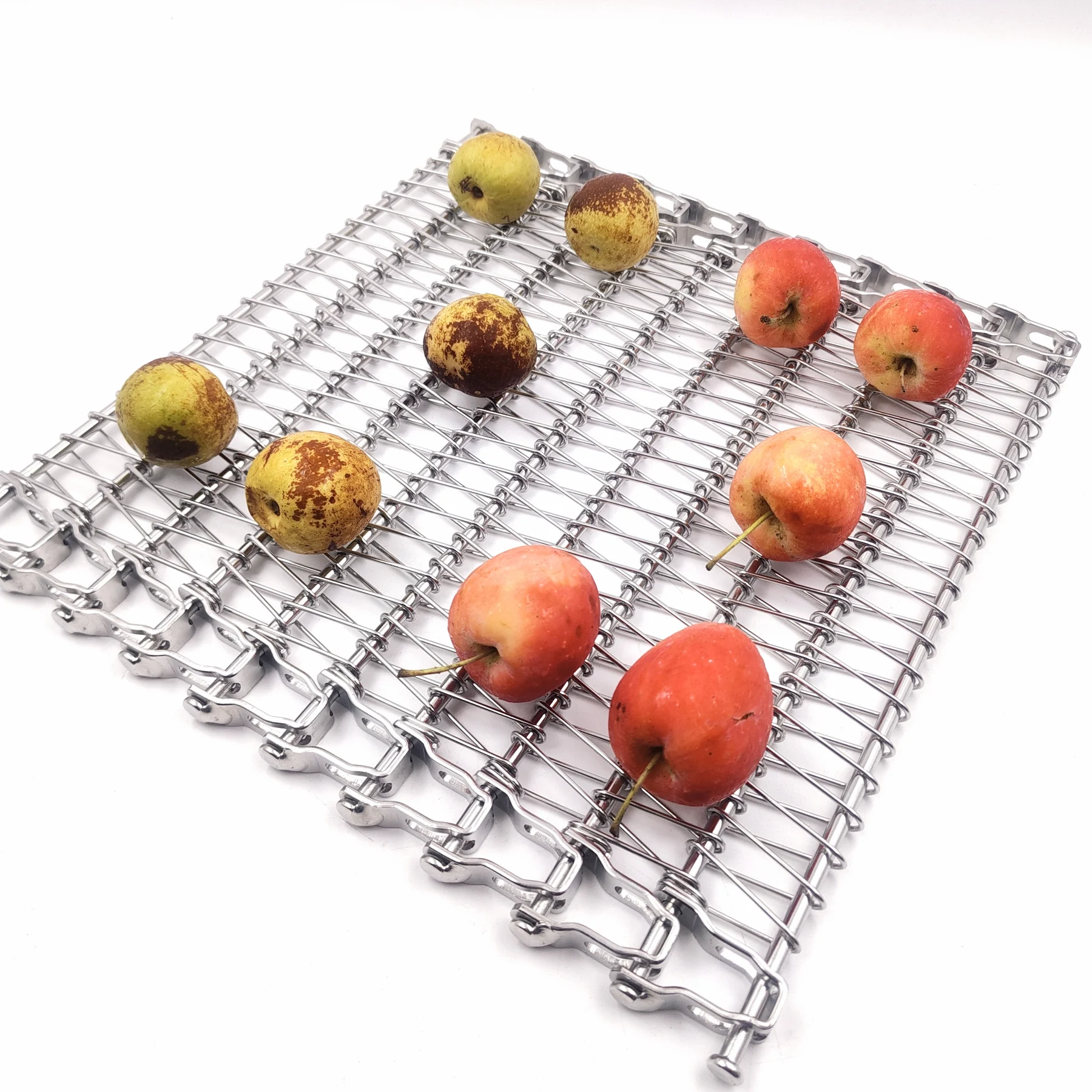 Mixed red and yellow whole fruit arranged on an open metal conveyor belt.