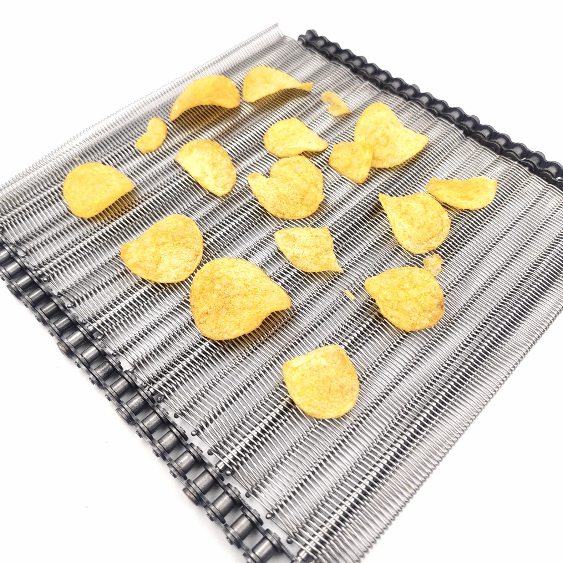 Golden curved chips arranged on a fine metal conveyor belt.