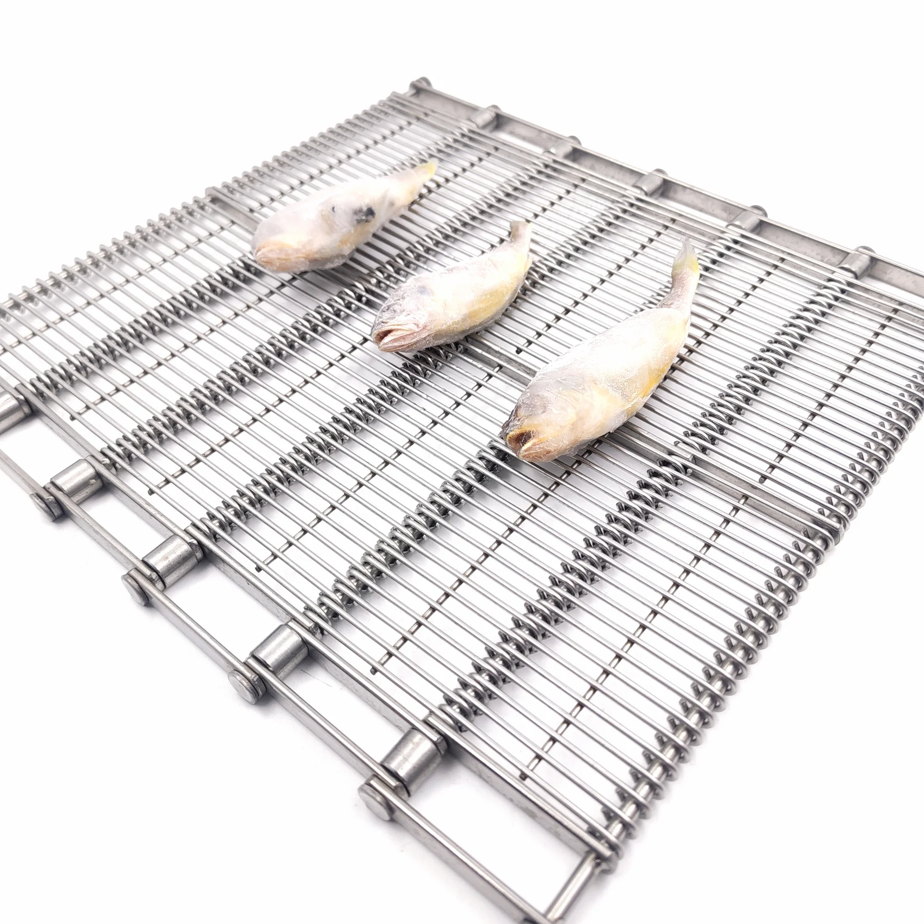 Frosted whole fish displayed on a linked open-wire metal conveyor belt.