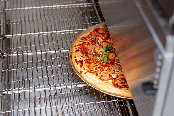 pizza being baked in industrial oven, fast food restaurant